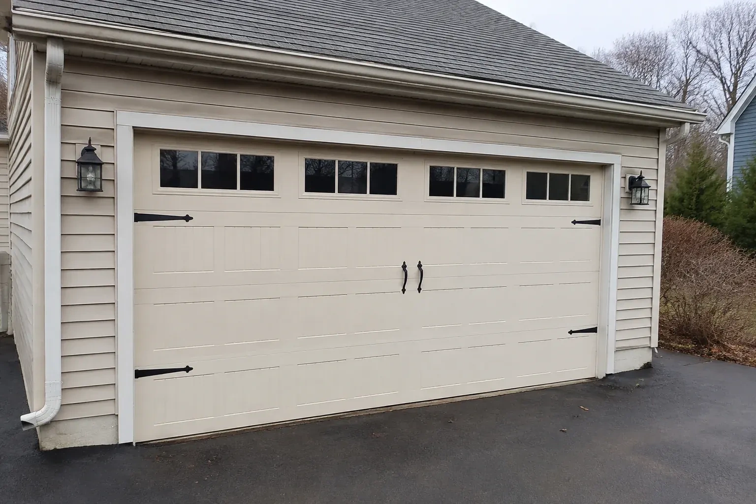 Cream carriage-house-style garage door with dark decorative hardware. — Carriage-House Garage Door Installation, Burlington